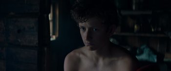 Movie still from “Out Stealing Horses” (2019), directed by Hans Petter Moland – A young man is looking at the camera; Close Up shot, High angle