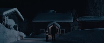 Movie still from “Out Stealing Horses” (2019), directed by Hans Petter Moland – A man and a dog standing in front of a snow covered house; Extreme Wide shot, Low angle