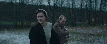 Movie still from “Out Stealing Horses” (2019), directed by Hans Petter Moland – A woman standing next to a man in a field; Medium shot, Low angle