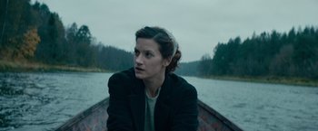 Movie still from “Out Stealing Horses” (2019), directed by Hans Petter Moland – A woman sitting in a boat on a river; Close Up shot, High angle