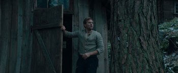 Movie still from “Out Stealing Horses” (2019), directed by Hans Petter Moland – A man standing in front of a wooden door; Medium shot, Low angle