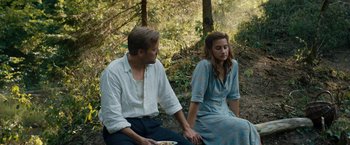 Movie still from “Out Stealing Horses” (2019), directed by Hans Petter Moland – A man and a woman sitting on the ground in the woods; Medium shot, High angle
