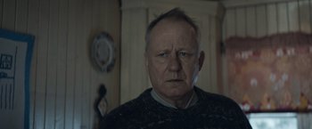 Movie still from “Out Stealing Horses” (2019), directed by Hans Petter Moland – An older man with a serious look on his face; Close Up shot, Low angle