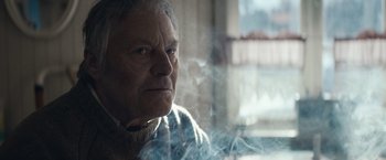 Movie still from “Out Stealing Horses” (2019), directed by Hans Petter Moland – An older man is looking out a window; Close Up shot, Low angle