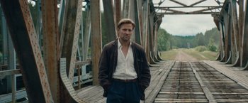 Movie still from “Out Stealing Horses” (2019), directed by Hans Petter Moland – A man standing on top of a wooden bridge; Medium shot, Low angle