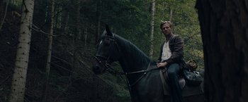 Movie still from “Out Stealing Horses” (2019), directed by Hans Petter Moland – A man sitting on the back of a black horse; Wide shot, Low angle