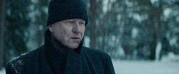 Movie still from “Out Stealing Horses” (2019), directed by Hans Petter Moland – An older man wearing a black coat and a black hat; Close Up shot, Over the shoulder angle