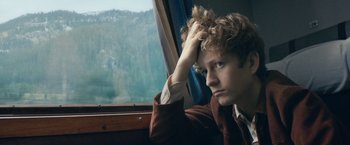 Movie still from “Out Stealing Horses” (2019), directed by Hans Petter Moland – A man sitting in front of a window with a mountain view; Close Up shot, High angle