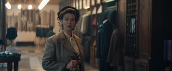 Movie still from “Out Stealing Horses” (2019), directed by Hans Petter Moland – A woman wearing a hat and a coat in a store; Medium shot, Over the shoulder angle