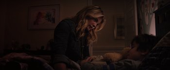 Movie still from “The 5th Wave” (2016), directed by J Blakeson – A woman sitting on top of a bed in a dark room; Medium shot, Over the shoulder angle