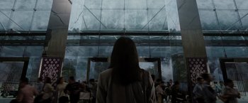 Movie still from “The 5th Wave” (2016), directed by J Blakeson – A woman standing in front of a glass building; Medium shot, Low angle
