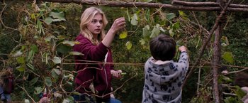 Movie still from “The 5th Wave” (2016), directed by J Blakeson – A young woman and a young boy in the woods; Medium shot, Over the shoulder angle