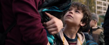Movie still from “The 5th Wave” (2016), directed by J Blakeson – A young boy looking at something in his backpack; Close Up shot, Over the shoulder angle