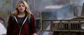 Movie still from “The 5th Wave” (2016), directed by J Blakeson – A woman in a red jacket is standing in front of a fire truck; Medium shot, Over the shoulder angle