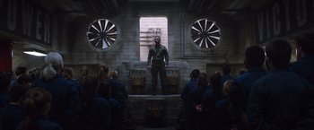 Movie still from “The 5th Wave” (2016), directed by J Blakeson – A group of people sitting in front of a man in uniform; Wide shot, Low angle