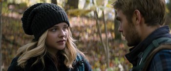 Movie still from “The 5th Wave” (2016), directed by J Blakeson – A young woman wearing a hat looking at a man in the woods; Close Up shot, Over the shoulder angle