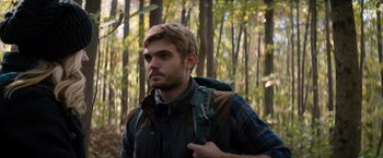 Movie still from “The 5th Wave” (2016), directed by J Blakeson – A man with a backpack walking through the woods; Close Up shot, Over the shoulder angle