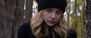 Movie still from “The 5th Wave” (2016), directed by J Blakeson – A person wearing a hat near a tree; Close Up shot, Over the shoulder angle