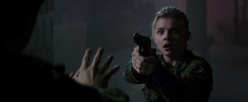 Movie still from “The 5th Wave” (2016), directed by J Blakeson – A woman holding a gun in her hand; Close Up shot, Over the shoulder angle