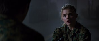 Movie still from “The 5th Wave” (2016), directed by J Blakeson – A woman in a camouflage jacket looking at the camera; Close Up shot, Over the shoulder angle