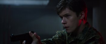 Movie still from “The 5th Wave” (2016), directed by J Blakeson – A young man holding a cell phone while wearing a camouflage jacket; Close Up shot, Low angle