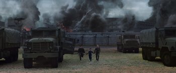 Movie still from “The 5th Wave” (2016), directed by J Blakeson – Two men and a child walking in front of a large fire truck; Extreme Wide shot, Low angle