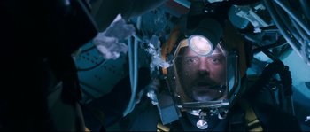 Movie still from “The Abyss” (1989), directed by James Cameron – A man wearing a diving suit with a head lamp on; Close Up shot, Overhead angle