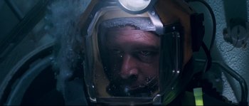 Movie still from “The Abyss” (1989), directed by James Cameron – A person wearing a diving helmet; Close Up shot, Overhead angle