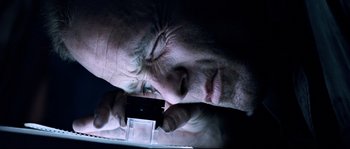 Movie still from “The Abyss” (1989), directed by James Cameron – An older man looking at a cell phone; Extreme Close Up shot, Overhead angle