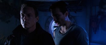 Movie still from “The Abyss” (1989), directed by James Cameron – A man with a beard is looking at another man in a dark room; Medium shot, Low angle