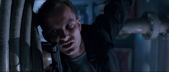 Movie still from “The Abyss” (1989), directed by James Cameron – A person holding a gun in a dark room; Close Up shot, Low angle