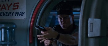 Movie still from “The Abyss” (1989), directed by James Cameron – A man holding a gun while standing next to a window; Close Up shot, Low angle