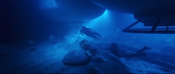 Movie still from “The Abyss” (1989), directed by James Cameron – A person swimming in the ocean under a boat; Extreme Wide shot, High angle