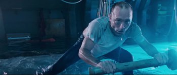 Movie still from “The Abyss” (1989), directed by James Cameron – A man is laying on the ground in the water; Medium shot, Overhead angle