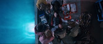 Movie still from “The Abyss” (1989), directed by James Cameron – A group of people gathered around looking at a laptop computer; Wide shot, Overhead angle