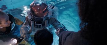 Movie still from “The Abyss” (1989), directed by James Cameron – A person in a space suit in a pool of water; Medium shot, Overhead angle
