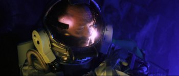Movie still from “The Abyss” (1989), directed by James Cameron – A man in a space helmet is looking into a mirror; Close Up shot, Overhead angle