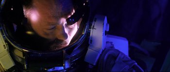 Movie still from “The Abyss” (1989), directed by James Cameron – A man in a space suit in a dark room; Close Up shot, Overhead angle