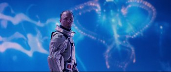 Movie still from “The Abyss” (1989), directed by James Cameron – A man standing in front of an image of a space ship; Medium shot, Low angle