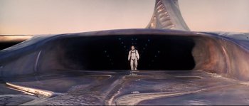 Movie still from “The Abyss” (1989), directed by James Cameron – A man in a spacesuit standing in front of an entrance to a space station; Wide shot, Overhead angle