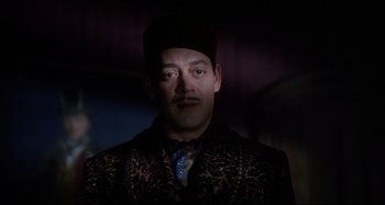 Movie still from “The Addams Family” (1991), directed by Barry Sonnenfeld – A person wearing a suit and hat; Close Up shot, Over the shoulder angle