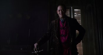 Movie still from “The Addams Family” (1991), directed by Barry Sonnenfeld – A man in a suit and tie holding a bicycle; Medium shot, Low angle