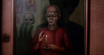 Movie still from “The Addams Family” (1991), directed by Barry Sonnenfeld – A painting of a man holding a lit candle; Medium shot, Overhead angle