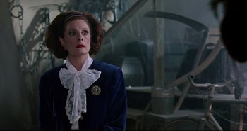 Movie still from “The Addams Family” (1991), directed by Barry Sonnenfeld – A woman wearing a blue jacket and a white bow tie; Medium shot, Over the shoulder angle