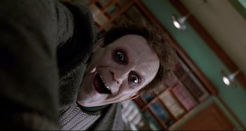 Movie still from “The Addams Family” (1991), directed by Barry Sonnenfeld – A person with a joker mask; Extreme Close Up shot, Overhead angle