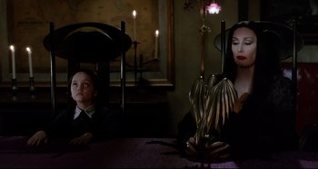 Movie still from “The Addams Family” (1991), directed by Barry Sonnenfeld – A woman and a child sitting at a table; Medium shot, Over the shoulder angle