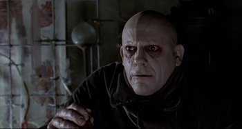 Movie still from “The Addams Family” (1991), directed by Barry Sonnenfeld – A man with a bald head wearing a black robe; Close Up shot, Low angle