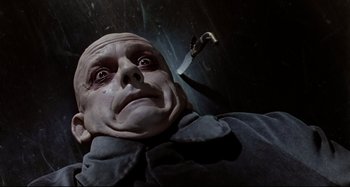 Movie still from “The Addams Family” (1991), directed by Barry Sonnenfeld – The face of a man with a knife in his hand; Close Up shot, Low angle