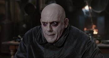 Movie still from “The Addams Family” (1991), directed by Barry Sonnenfeld – A man with a bald head wearing a black jacket; Close Up shot, Low angle