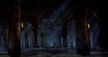 Movie still from “The Addams Family” (1991), directed by Barry Sonnenfeld – A person is sitting on a chair in the middle of a dark room; Extreme Wide shot, High angle